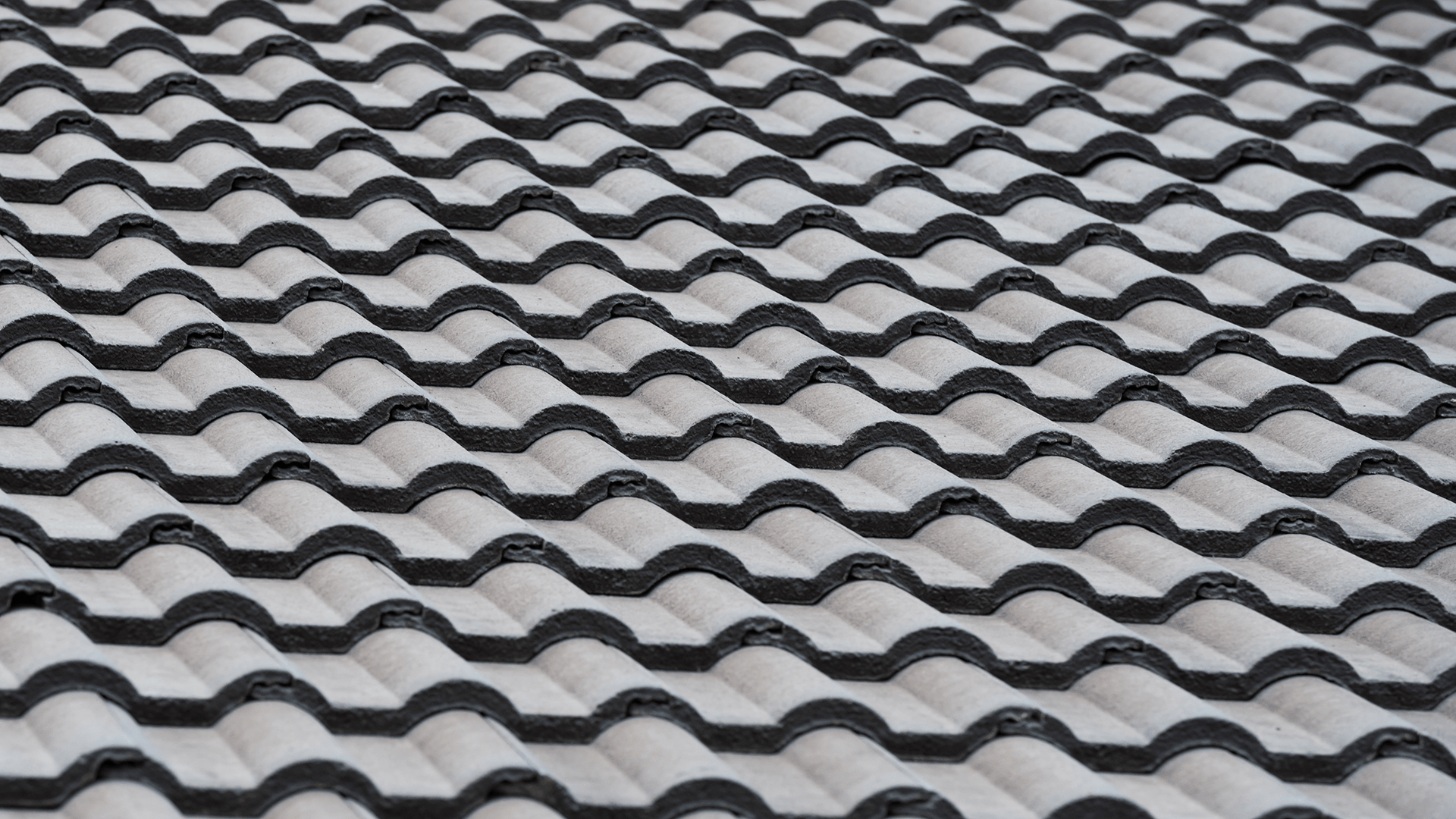 Dachfläche mit hellgrauen Betondachsteinen in Wellenform